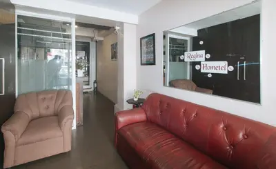 a living room with a red leather couch and two chairs at RedDoorz at Regina Hometel J Victor in Manila