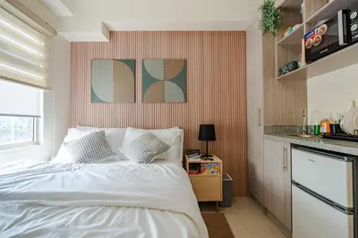 a bedroom with a white bed and a kitchen at SSM Staycation in Manila