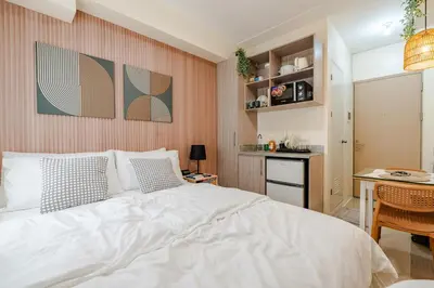 a bedroom with a bed and a table and a kitchen at SSM Staycation in Manila