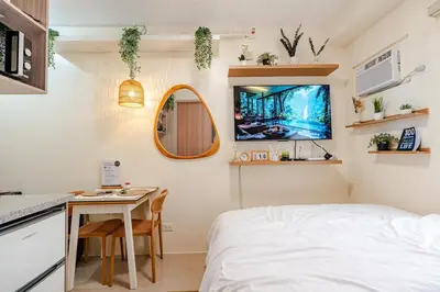 a bedroom with a bed and a table and a tv at SSM Staycation in Manila