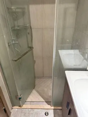 a shower with a glass door next to a sink at Condotel by Heidi in Manila
