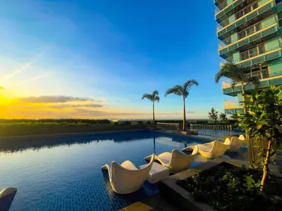a swimming pool with white chairs and a building at Spacious 5-Bedroom Luxury Apartment Across Okada in Manila