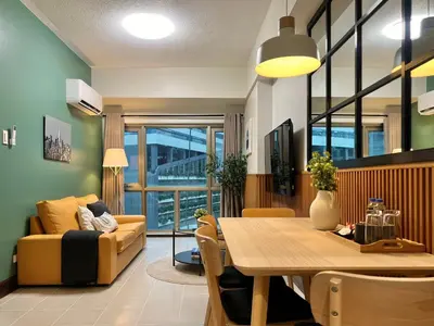 a living room with a table and a couch at Spacious 1BR with 300MBPS Internet near High Street BGC in Manila