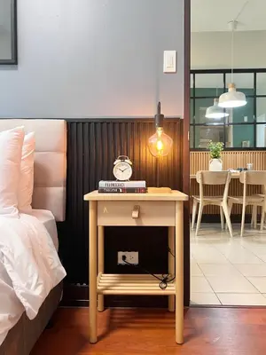 a bedroom with a bed and a table with a clock on it at Spacious 1BR with 300MBPS Internet near High Street BGC in Manila