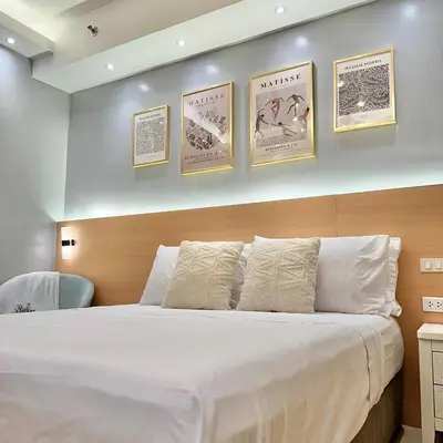 a bedroom with a large white bed with four pictures on the wall at Stylish Studio Unit with Balcony in Grace Residences in Manila