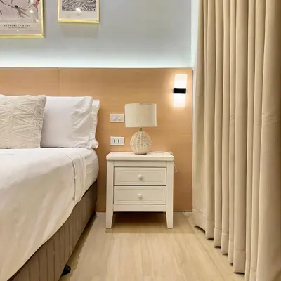 a bedroom with a bed and a night stand with a lamp at Stylish Studio Unit with Balcony in Grace Residences in Manila