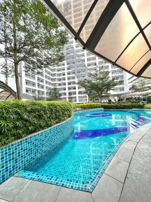 a swimming pool with blue tiles in front of a building at Stylish Studio Unit with Balcony in Grace Residences in Manila