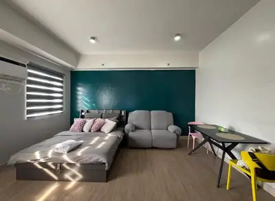 a bedroom with a bed and a chair and a table at Condo near SM City Sta Rosa unit 4 in Ibaba