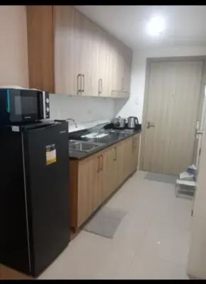 a kitchen with a black refrigerator and wooden cabinets at Sam's crib staycation in Manila