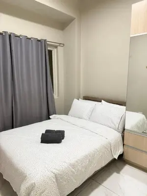 a bedroom with a white bed with a black object on it at Condo Monarch Parksuites in Sampong