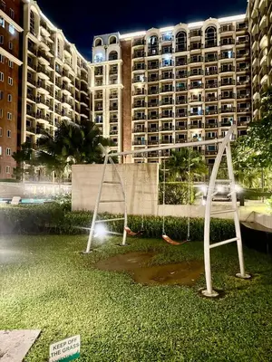 a park with swings in front of a large building at Condo Monarch Parksuites in Sampong