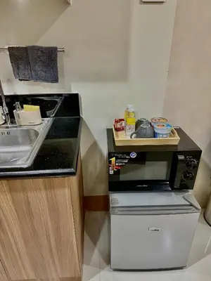 a kitchen with a sink and a counter with a dishwasher at Soléa Suites in Manila