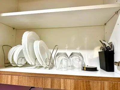 a shelf with white plates and glasses on it at Soléa Suites in Manila