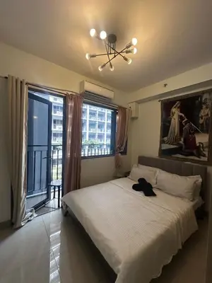 a bedroom with a large bed and a chandelier at Shore 2 tower 1 by Richnells cozy Oasis in Manila