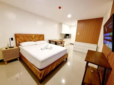 a bedroom with a large bed and a kitchen at Flat 35, Unit 1C in Manila