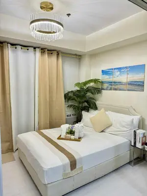 a bedroom with a large white bed and a chandelier at Azure residences by Amóre Suites in Manila