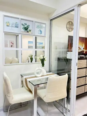 a dining room with a glass table and white chairs at Azure residences by Amóre Suites in Manila