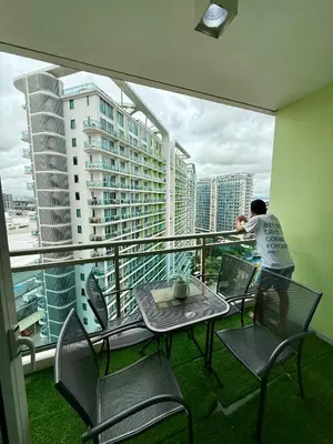 a man standing on a balcony with a table and chairs at Azure residences by Amóre Suites in Manila