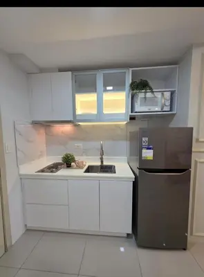 a kitchen with white cabinets and a sink and a refrigerator at Jazz Haven Makati in Manila