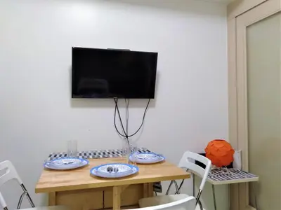 a table with chairs and a television on a wall at My Cozy Little Crib - Sea Residence - Tower C in Manila