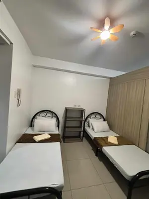 a room with two beds and a ceiling fan at 3 single beds transient room mall of asia pasay in Manila