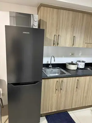 a kitchen with a black refrigerator and a sink at 3 single beds transient room mall of asia pasay in Manila