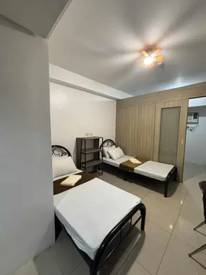 a room with two beds and a ceiling fan at 3 single beds transient room mall of asia pasay in Manila