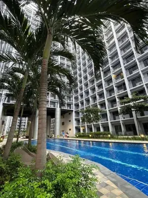 a large building with palm trees in front of a swimming pool at 3 single beds transient room mall of asia pasay in Manila
