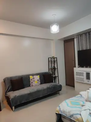 a living room with a couch and a television at Kmad's Condotel in Manila
