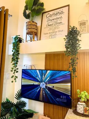 a flat screen tv on a wall with plants at Twins Nest - CASA VICENTE Cozy 2-Bedroom Loft Condo Mandaluyong in Manila