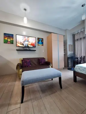 a living room with a couch and a tv on the wall at Eastwood Legrand3 Studio Type condo in Manila
