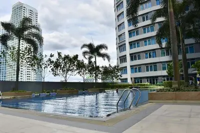 a swimming pool with palm trees and a building at Eastwood Legrand3 Studio Type condo in Manila