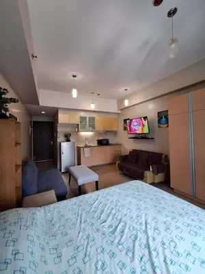 a bedroom with a large bed and a living room at Eastwood Legrand3 Studio Type condo in Manila
