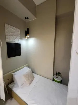 a small bedroom with a white bed and a television at Amazing 1 5BR unit Connected to Eastwood Mall in Manila