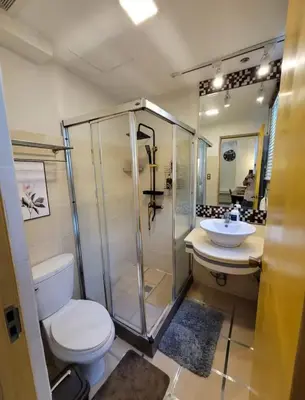 a bathroom with a shower and a toilet and a sink at Stunning Suite 10 Steps from Eastwood Mall in Manila