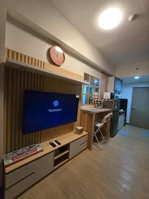 a living room with a large tv and a clock on the wall at The Beacon Haven in Trece Martires
