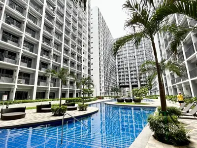 a swimming pool with palm trees and buildings at ClaySky Staycation at Shore 2 Residences Tower 2 near Mall of Asia- Hotel Set Up in Amenity and Pool Level with Netflix, HBO Max & Youtube Premium in Manila