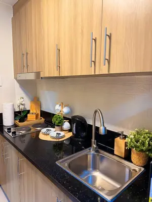 a kitchen with a stainless steel sink and wooden cabinets at Newly-furnished 1BR with Balcony near MRT Mandaluyong in Manila
