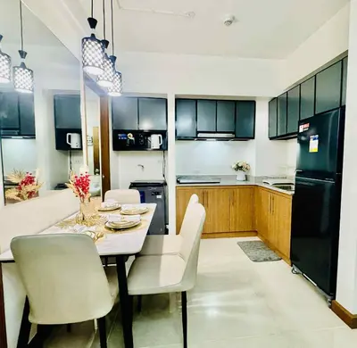 a kitchen with a table and chairs and a black refrigerator at Palm Beach West - Baler Tower in Manila