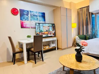 a living room with a bed and a table with a television at Kozy Mood Studio in Manila