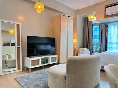 a living room with a television and a bedroom at Kozy Mood Studio in Manila