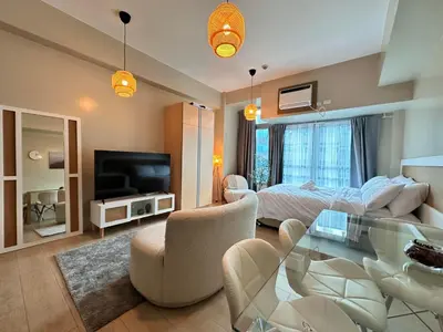 a living room with a bed and a glass table at Kozy Mood Studio in Manila