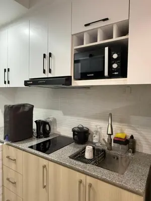 a kitchen with white cabinets and a sink and a microwave at Flat 316 Modern Minimalist Studio Near Makati BGC in Manila