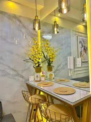 a dining room with a table with chairs and yellow flowers at Golden Sunset Suite in Manila