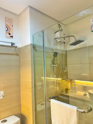 a bathroom with a glass shower with a toilet at Golden Sunset Suite in Manila