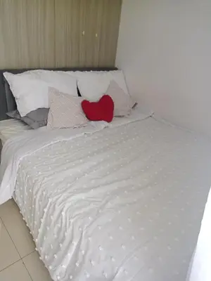 a white bed with a red heart pillow on it at Like home staycation in Manila
