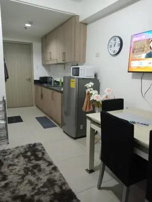 a kitchen with a refrigerator and a table and a clock at Like home staycation in Manila