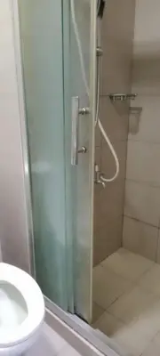a bathroom with a shower with a toilet and a sink at Like home staycation in Manila