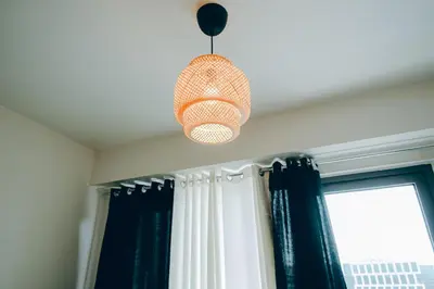 a pendant light hanging over a window with curtains at Budget staycation near moa in Manila
