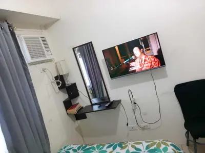a room with a tv on a wall with a bed at Zafreen Condotel in Manila